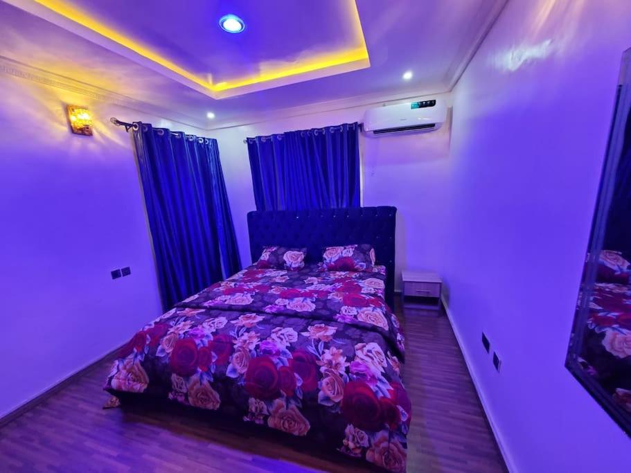 a bedroom with a bed with purple sheets and blue curtains at Vim 2-BR-Apt With Fast Unlimited Internet & 24HRS Power in Lagos