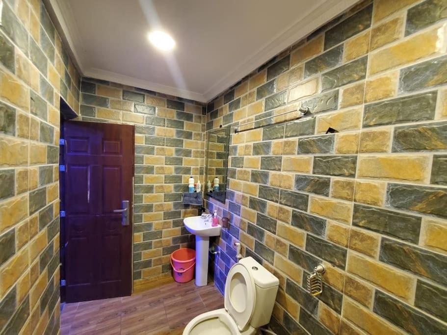 a brick bathroom with a toilet and a sink at Vim 2-BR-Apt With Fast Unlimited Internet & 24HRS Power in Lagos