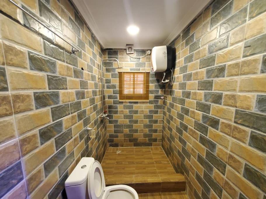 a bathroom with a toilet and a brick wall at Vim 2-BR-Apt With Fast Unlimited Internet & 24HRS Power in Lagos