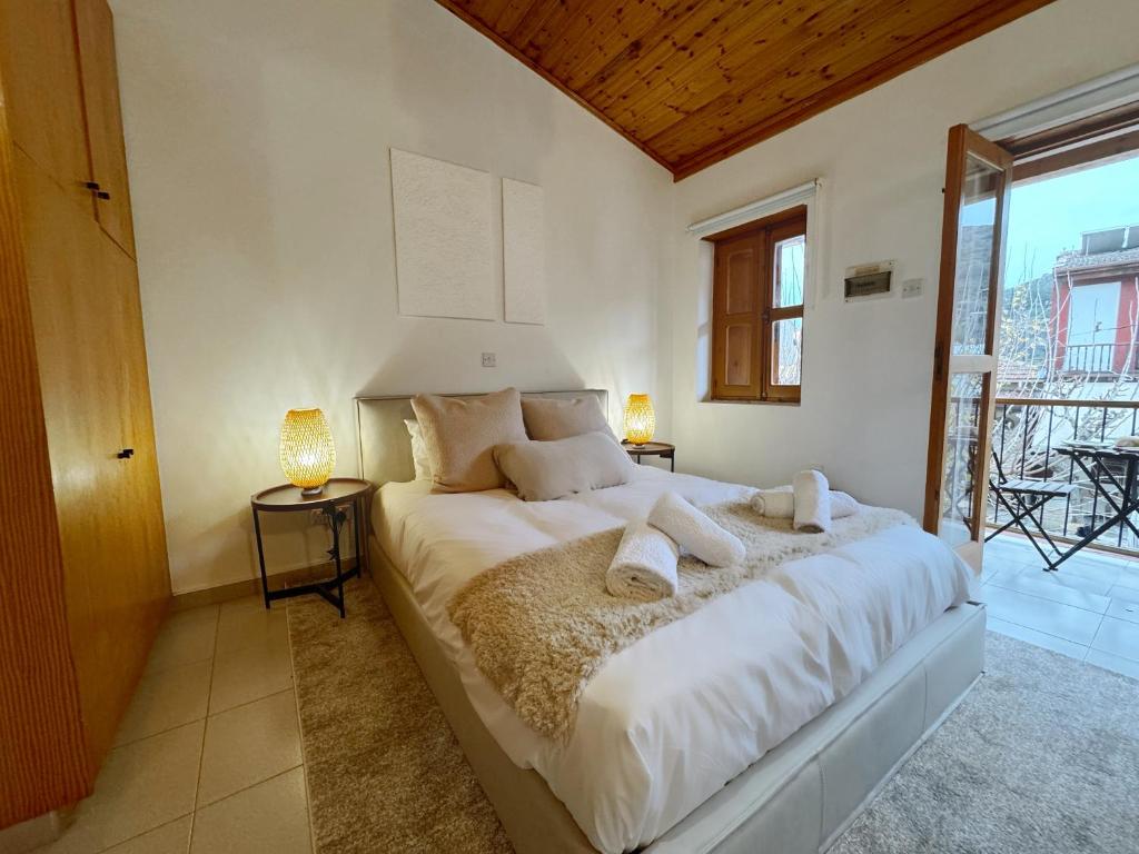 1 dormitorio con 1 cama grande con sábanas y almohadas blancas en Maison Damianou Elegant Loft, en Omodos