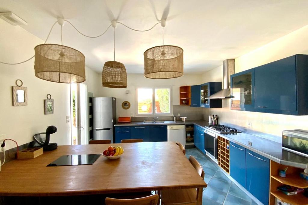 モーギオにあるThe seaside 200m2 villa with swimming pool!のキッチン(青いキャビネット、木製テーブル付)