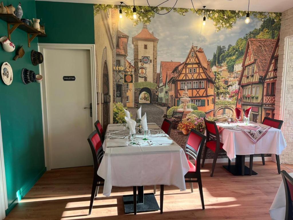 a dining room with two tables and a mural on the wall at Hôtel Le Pommeil in Guéret