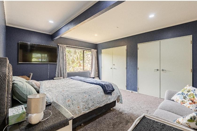 a bedroom with blue walls and a bed and a couch at Lux. Room with Ensuite in Kelburn