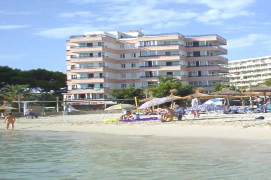 una playa con un edificio y gente en la playa en Apartamentos Calablanca, en Palmanova