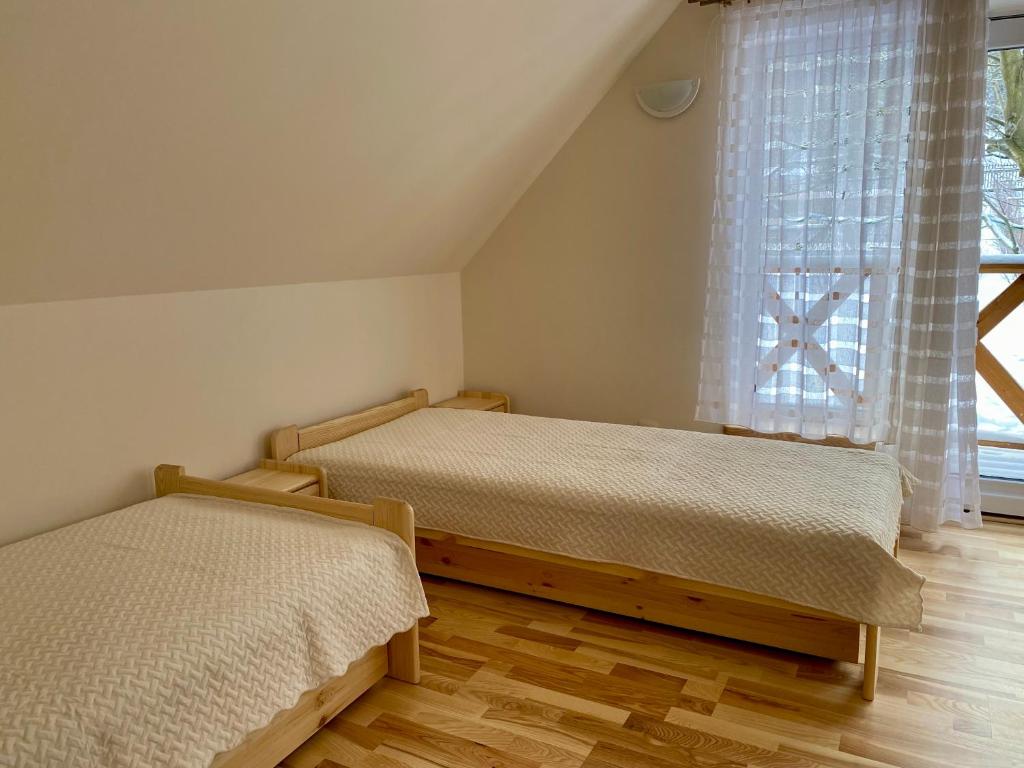 two beds in a room with a window at Apartament W Dolinie Modrzewi in Kamienna Góra