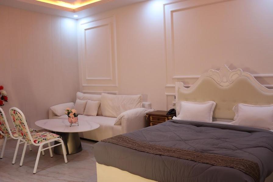 ein Schlafzimmer mit einem Bett, einem Sofa und einem Tisch in der Unterkunft Green Valley Seas and Resorts in Ranchi