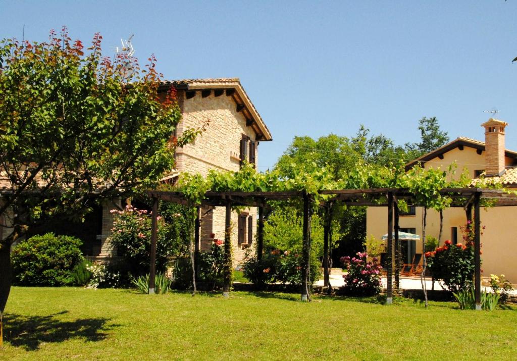 um jardim com uma pérgula em frente a uma casa em B&B Antegiano em Belforte del Chienti