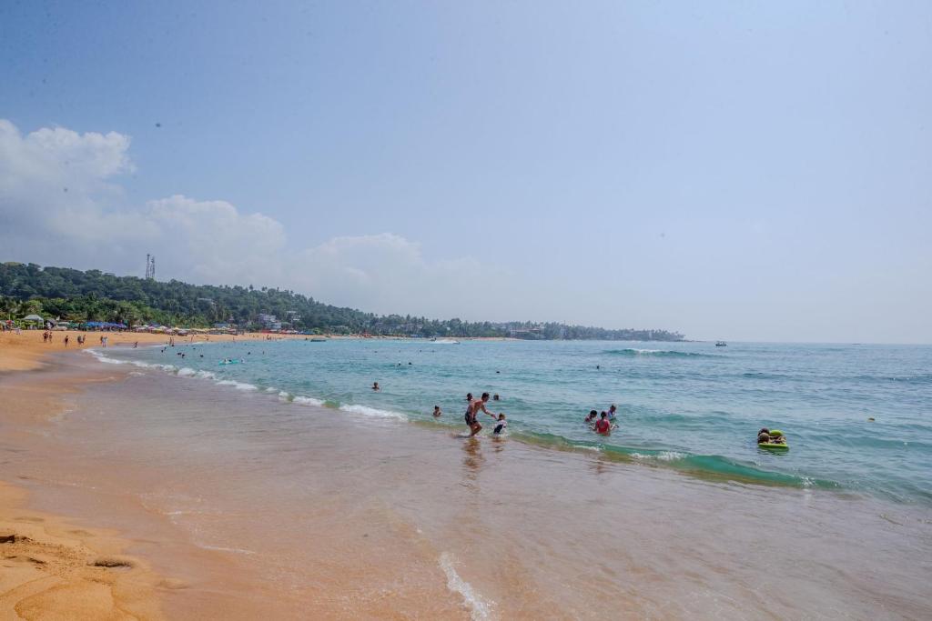 grupa ludzi bawiących się w wodzie na plaży w obiekcie The Waves Unawatuna w mieście Unawatuna