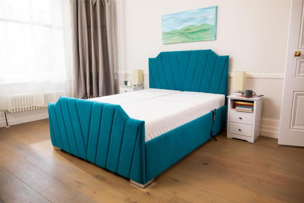 a bed with a blue headboard in a bedroom at Heaven in Cheam
