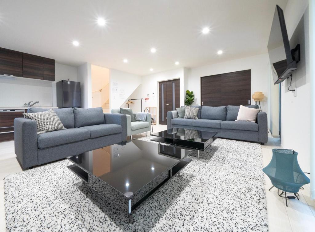 a living room with two couches and a tv at Rei Garden Resort in Kanayama