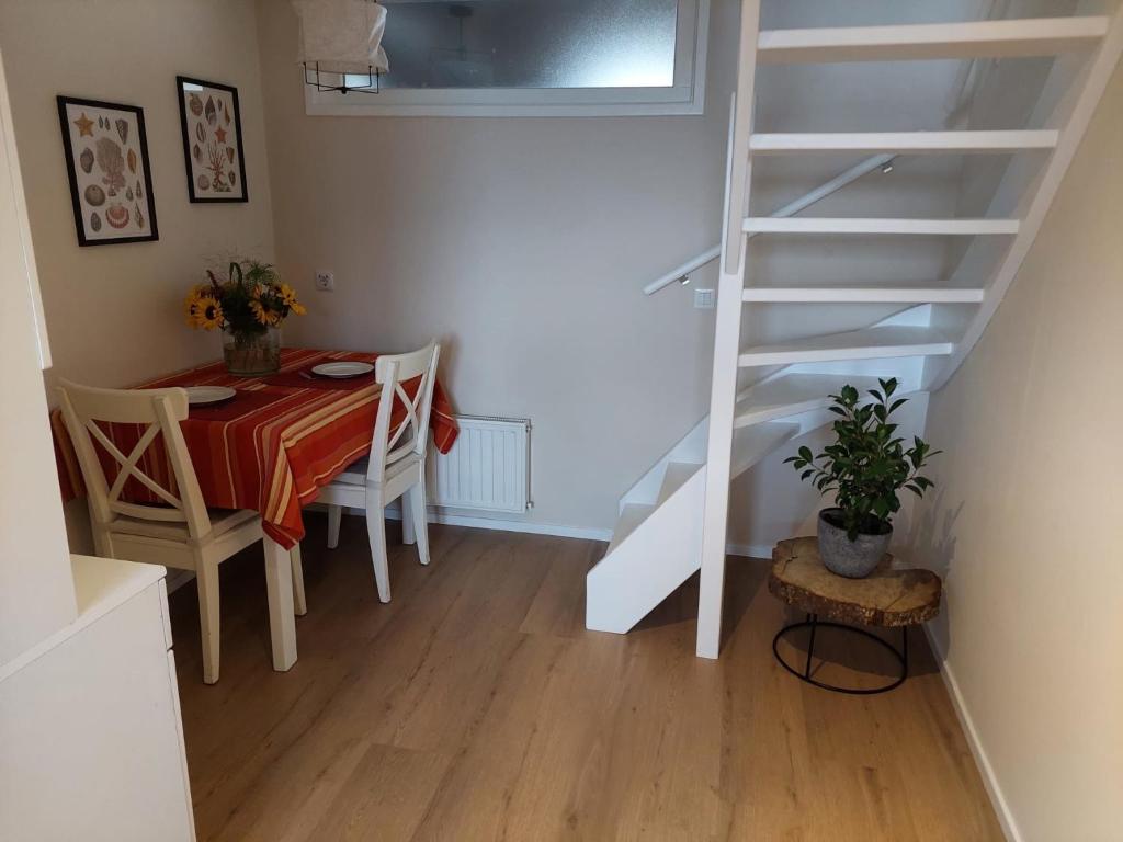 een eetkamer met een tafel en een witte trap bij Studio 8 in Zoutelande