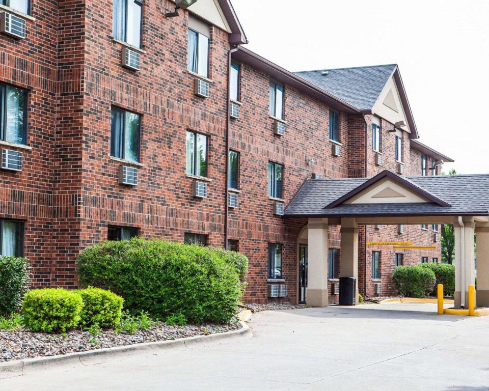 un grande edificio in mattoni rossi con cespugli di fronte di Quality Inn & Suites Ankeny-Des Moines ad Ankeny