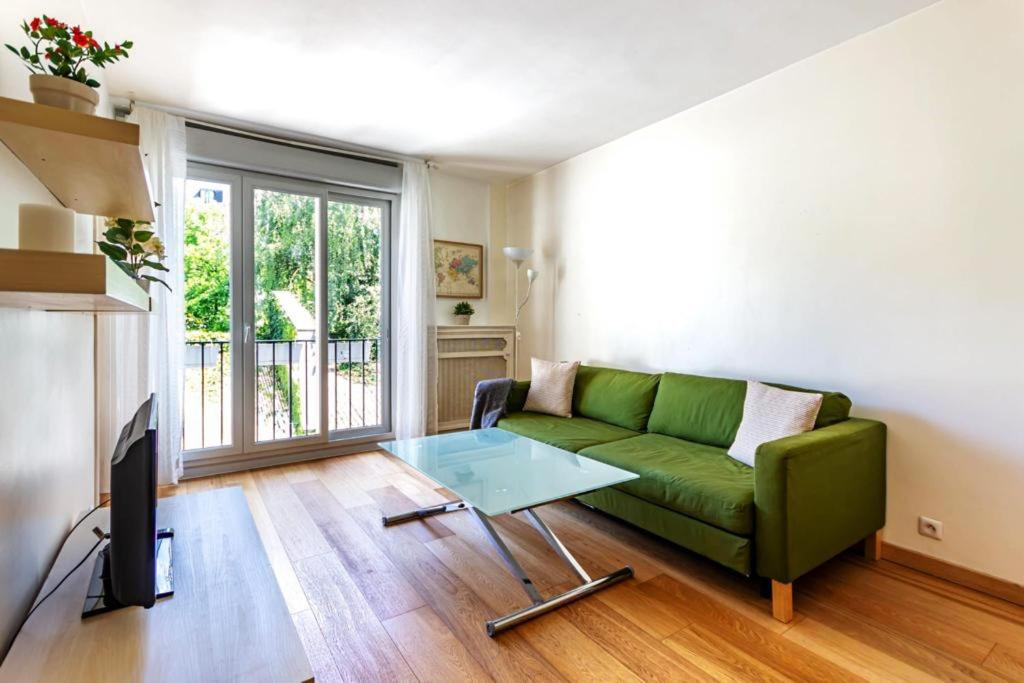 un soggiorno con divano verde e tavolo in vetro di The Parisian Dream a Parigi