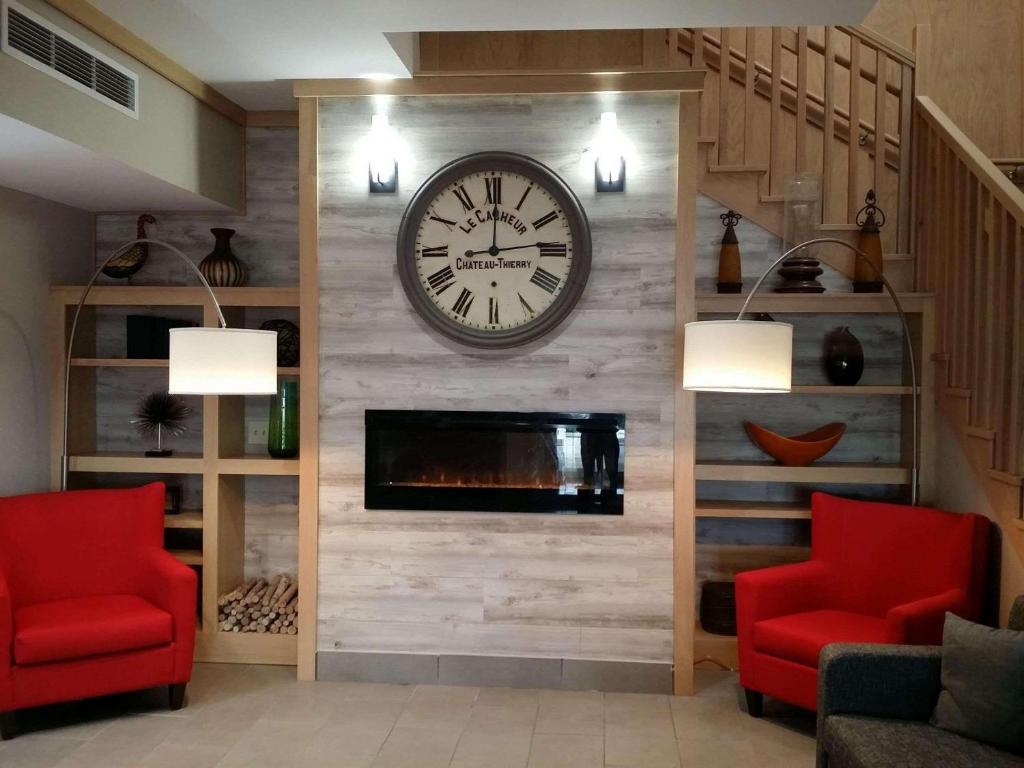 sala de estar con reloj y chimenea en Country Inn & Suites by Radisson, Gillette, WY, en Gillette