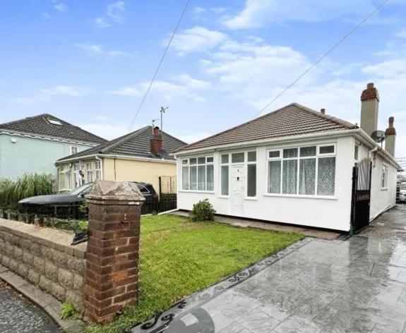 una casa blanca con un pilar de ladrillo en un patio en Uplands Grove Bungalow, en Wolverhampton