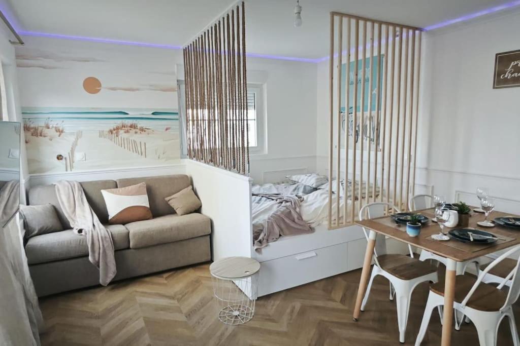 een woonkamer met een bank en een tafel bij Perle Berckoise - studio - 250m de la plage - 1er étage in Berck-sur-Mer