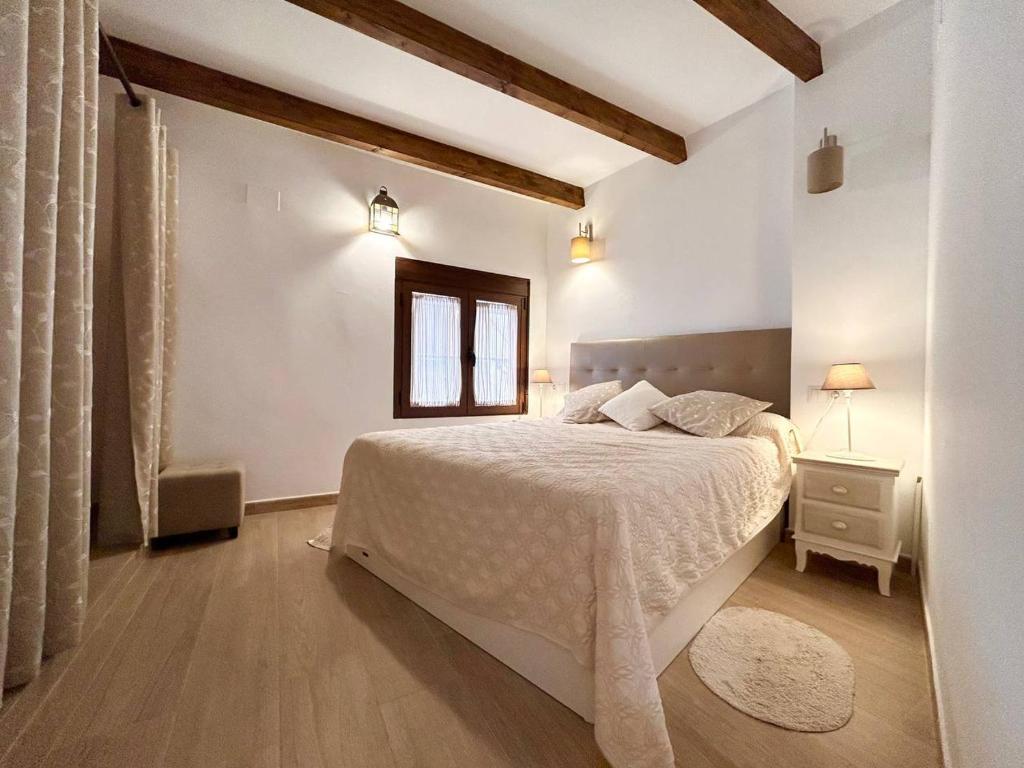 ein weißes Schlafzimmer mit einem Bett und einem Fenster in der Unterkunft Villajoyosa Family Apartment in Villajoyosa