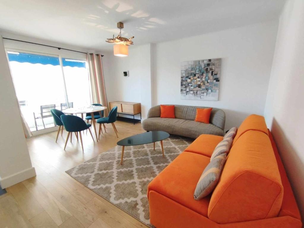 un salon avec un canapé orange et une table dans l'établissement Cannes Pointe Croisette T2 plage 2min à pieds 46m2, à Cannes