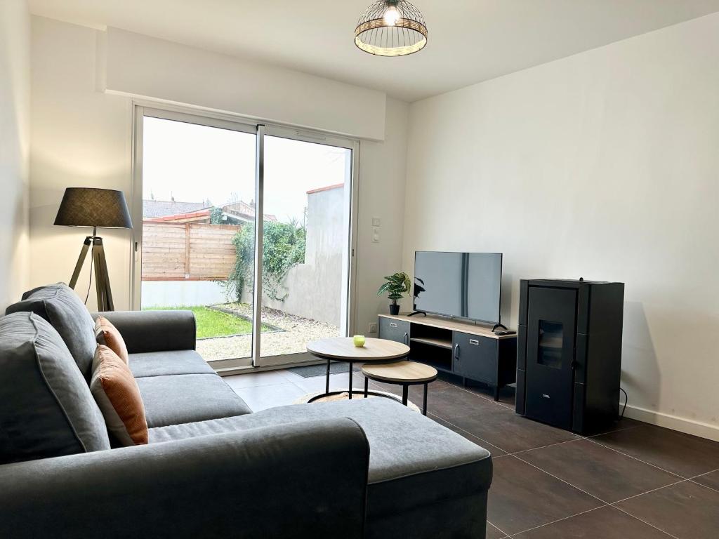 a living room with a couch and a tv at L'IMPÉRIAL - Jardin & Parking in Mont-de-Marsan