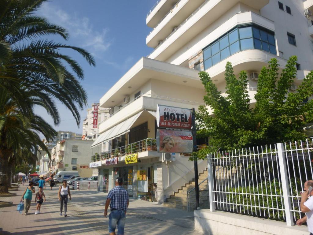 people walking down a street in front of a building at Hotel Rossi in Vlorë