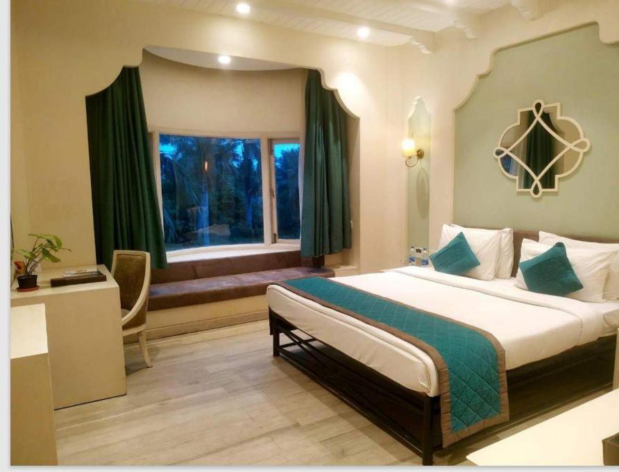 Ibiza The Fern Resort & Spa, Kolkata في كولْكاتا: غرفة نوم بسرير كبير ونافذة