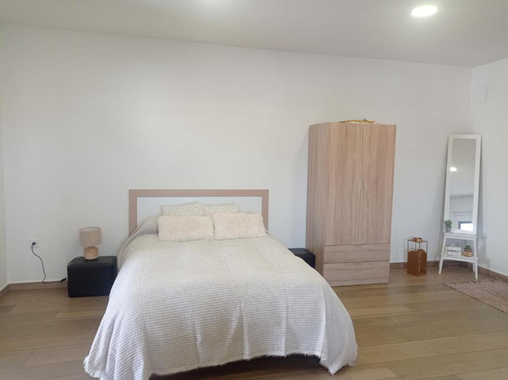 - une chambre blanche avec un lit et du parquet dans l'établissement Loft de 50metros con dos terrazas, à Herencia