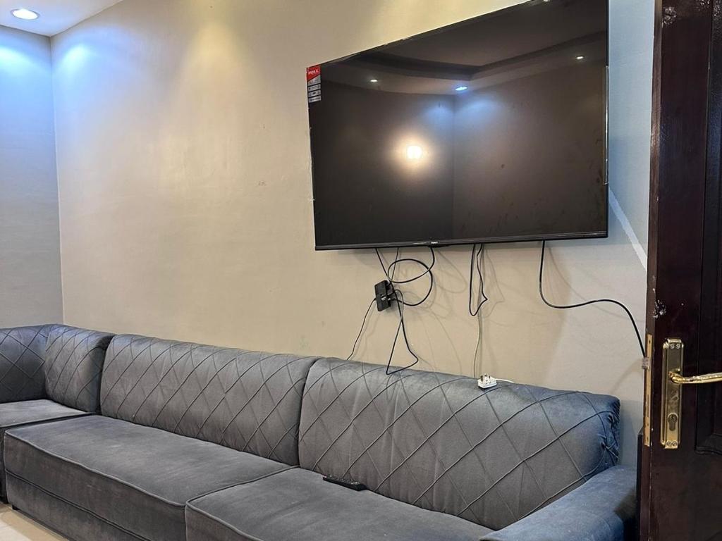 a couch with a flat screen tv on a wall at استراحة وشاليه وقاعة السلطانه in Al-Salam