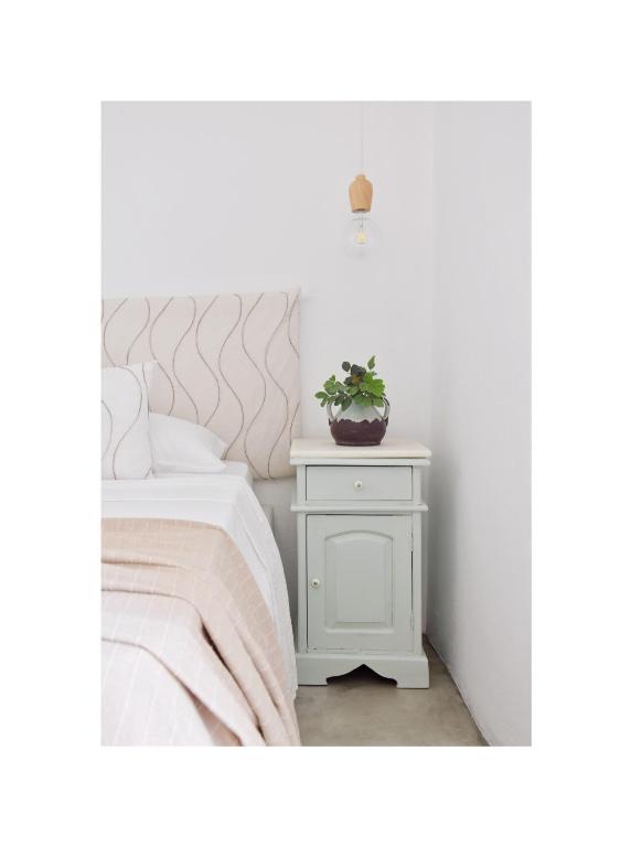 a white bed with a potted plant on a night stand at Koukounari Cottage Apartment Paros in Naousa