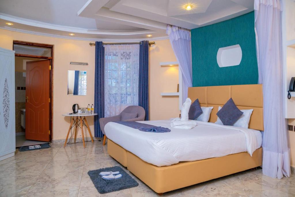 - une chambre avec un grand lit et un mur vert dans l'établissement Calfie Resort Kisumu, à Ahero