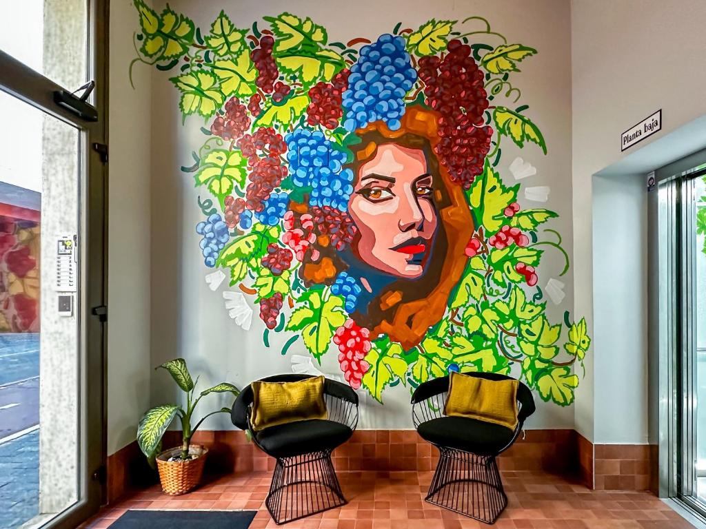 a mural of a woman with grapes on a wall at Coeo Parras Design Apartments in Málaga