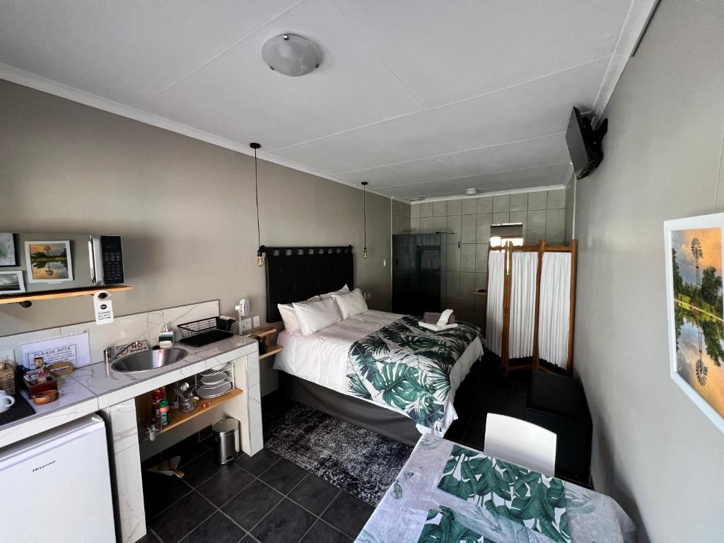 a small room with a bed and a sink in it at Midway En Route in Harrismith