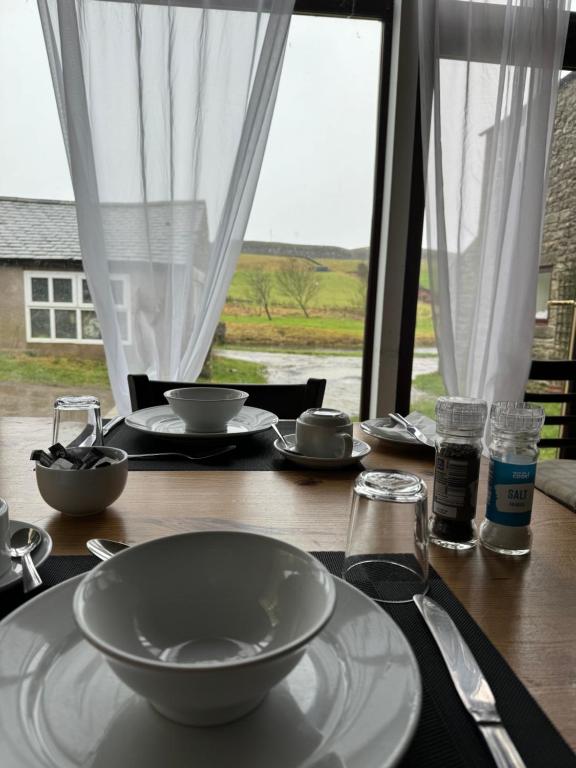 a wooden table with a bowl and plates on it at Saughy rigg farm in Haltwhistle