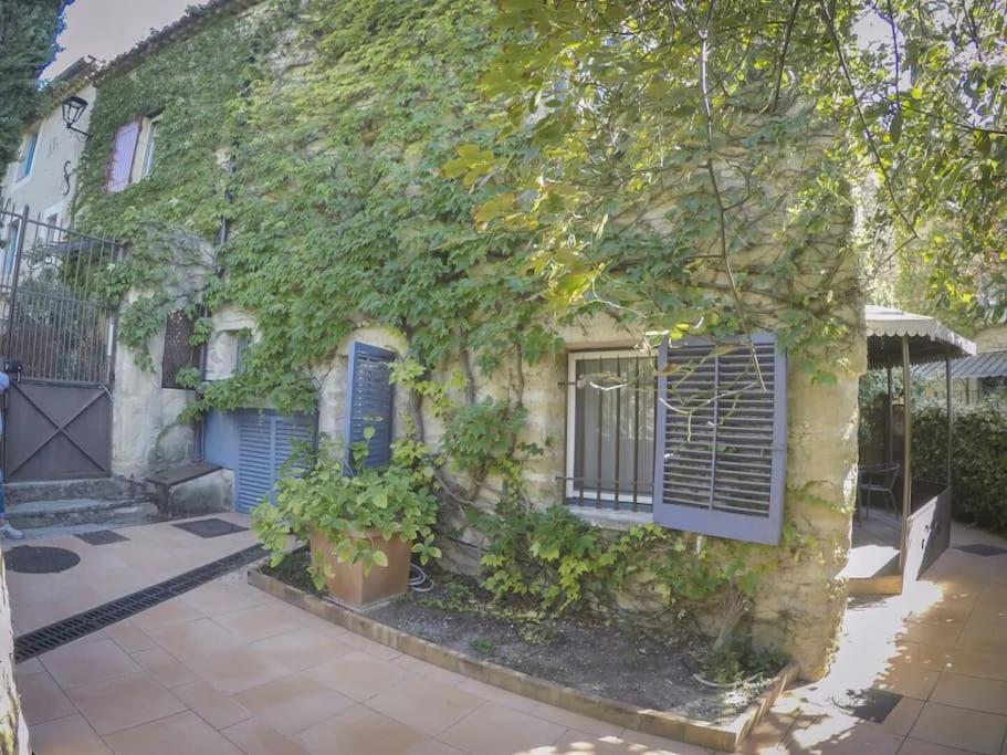 an ivy covered building with blue doors and windows at Appartement en pierre à proximité Lourmarin in Lauris
