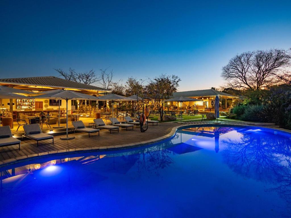 a swimming pool with chairs and umbrellas at night at Insika lodge in Victoria Falls