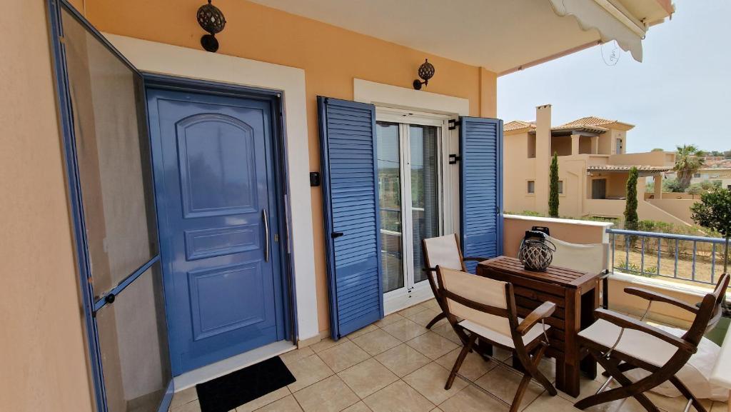 a blue door on a balcony with a table and chairs at Nala's home in Porto Heli