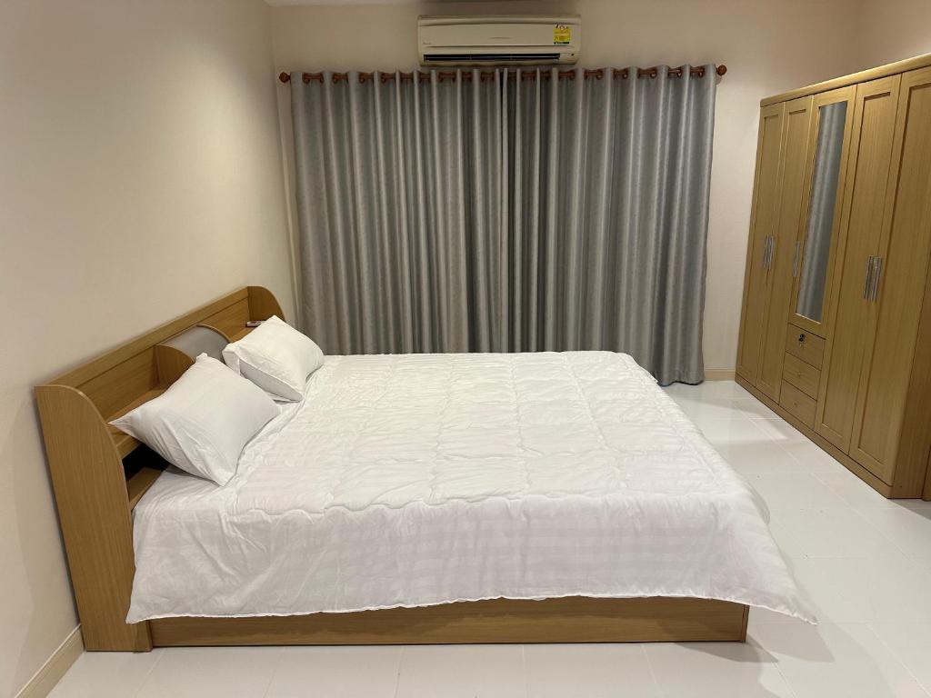 um quarto com uma cama com lençóis brancos e uma janela em Country Complex Bangna em Bangkok
