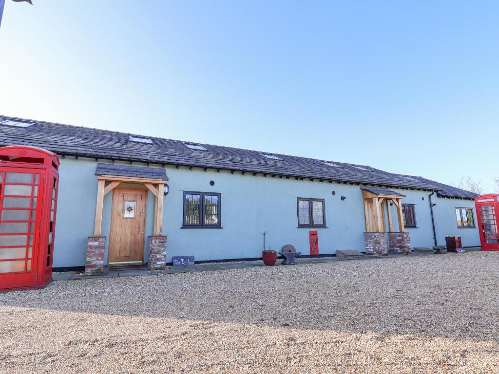 une maison avec deux cabines de téléphone rouge devant elle dans l'établissement The Shippon, à Frodsham