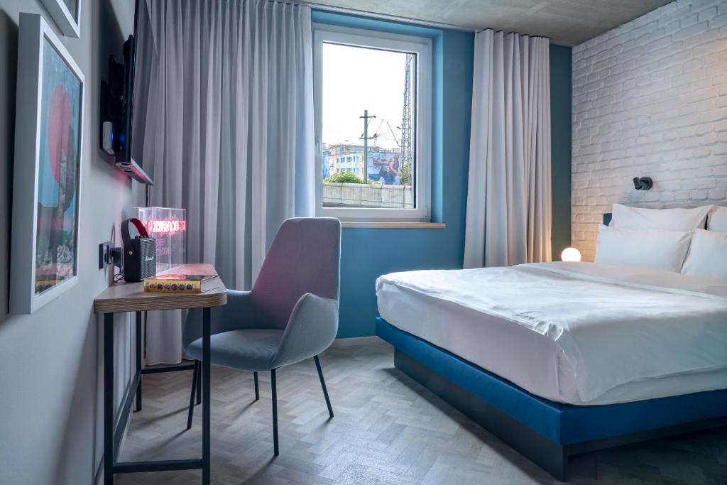 ケルンにあるURBAN LOFT Cologneのベッド、テーブル、椅子が備わるホテルルームです。