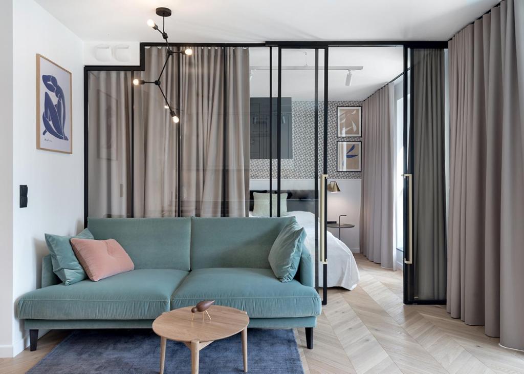 a living room with a blue couch in front of a bed at TOTU HOME Marina Gdańsk Modern Apartment in Gdańsk