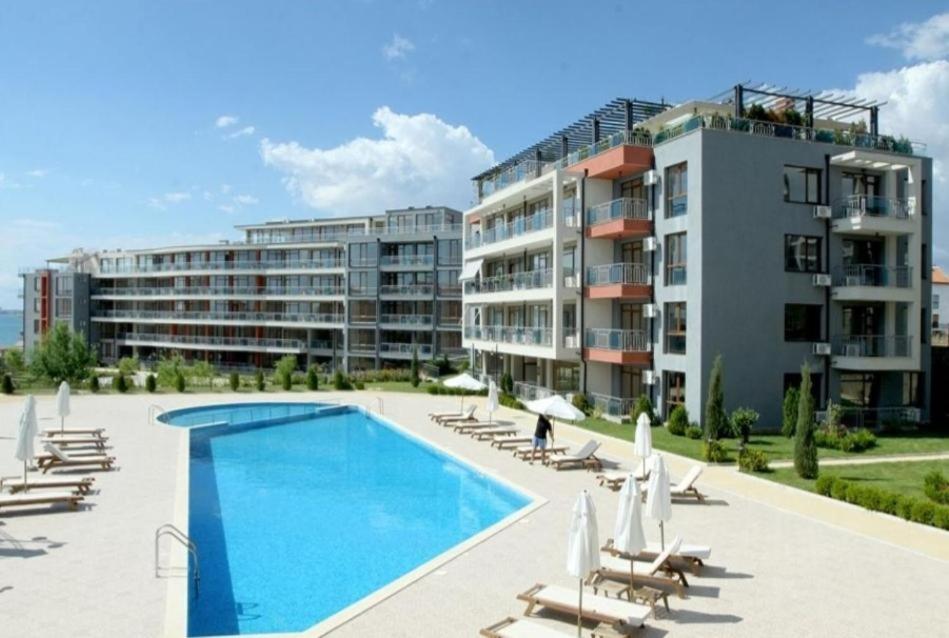 a resort with a swimming pool and chairs and a building at Sun Wave Sea and Pool View in Sveti Vlas