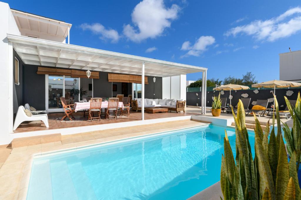 una piscina di fronte a una casa con patio di Villa Golf Lanzarote a Costa Teguise