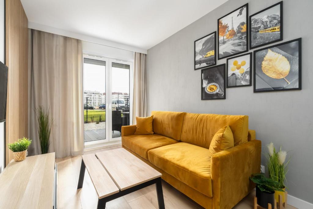 a living room with a yellow couch and a table at Spacious Apartments Niemena with FREE GARAGE by Renters in Poznań