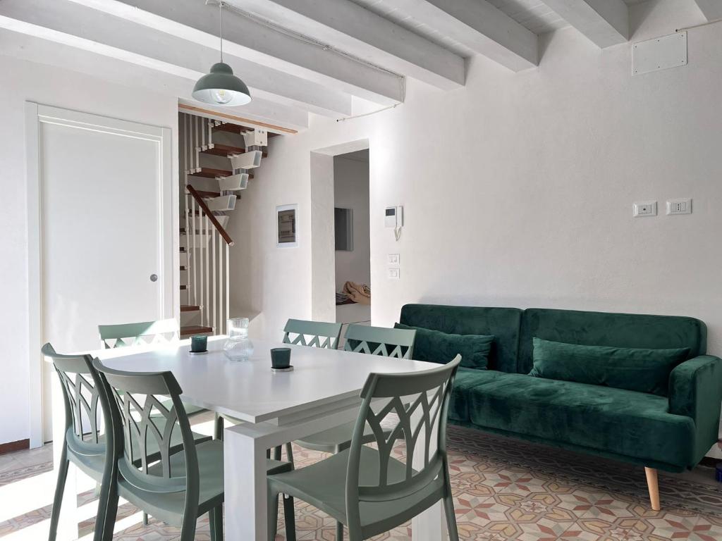 uma sala de estar com um sofá verde e uma mesa e cadeiras em M'AMA apartment em Ficarazzi