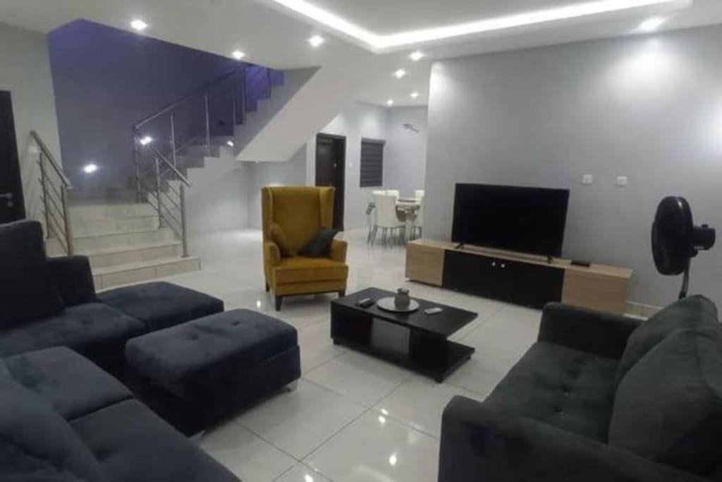 a living room with a couch and a tv and a chair at Luxe Living:4Bed, TV, Pool& WiFi in Lekki