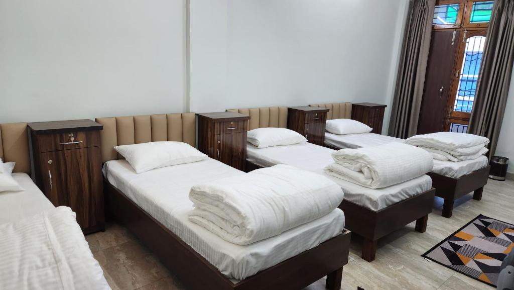 a room with four beds with white blankets at NANDI RETREAT HomeStay in Varanasi