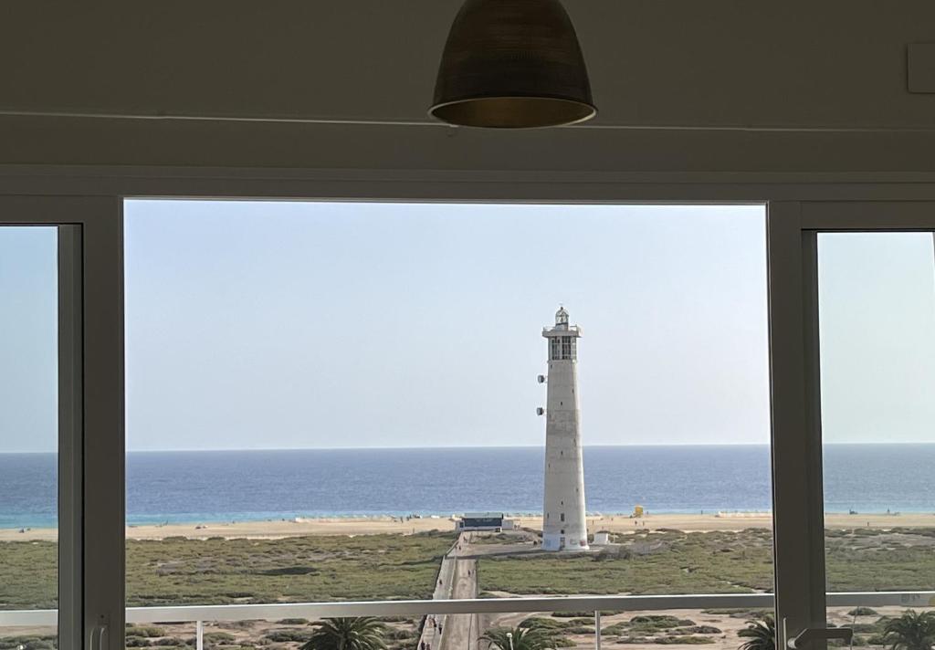 a view of a lighthouse from a room with a window at Blue Ocean Morro Jable in Morro del Jable
