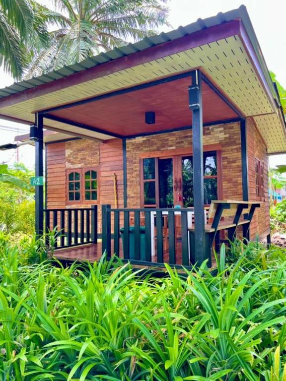 une petite maison avec une terrasse couverte dans un jardin dans l'établissement Lay Back Villa Wooden House AC Hot shower High Speed Internet, à Krabi