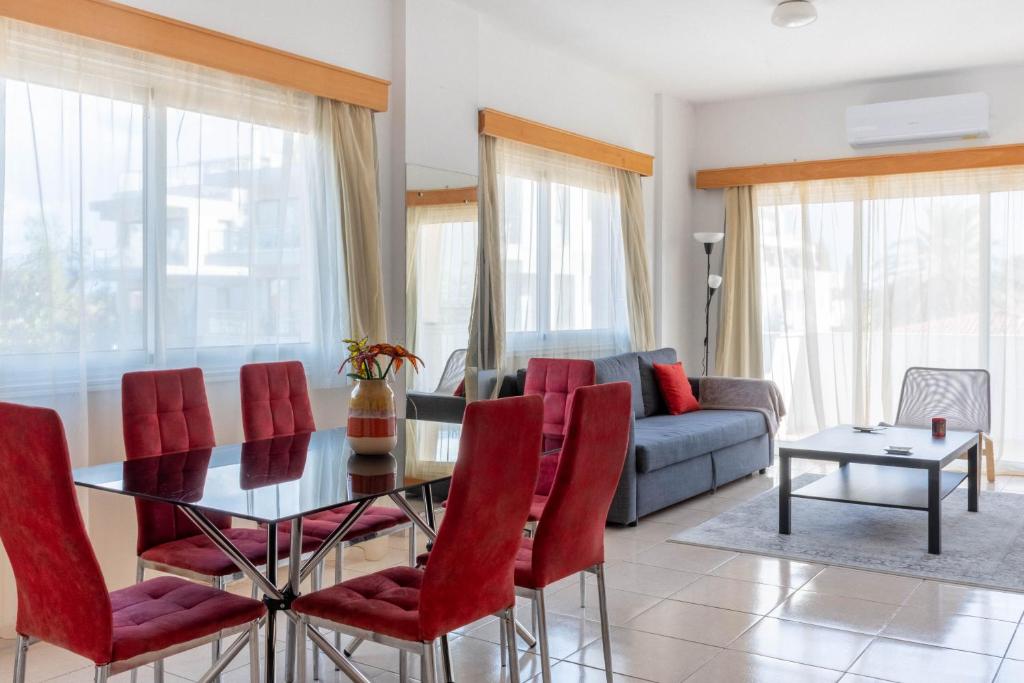 a living room with a glass table and red chairs at Princess Residence in Ayios Dhometios