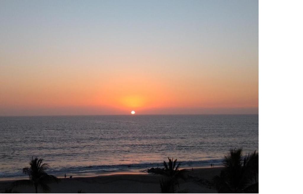 un tramonto sull'oceano con palme sulla spiaggia di Amazing Resort-air Gondola-pga Golf-beach-pool-spa a Nuevo Vallarta