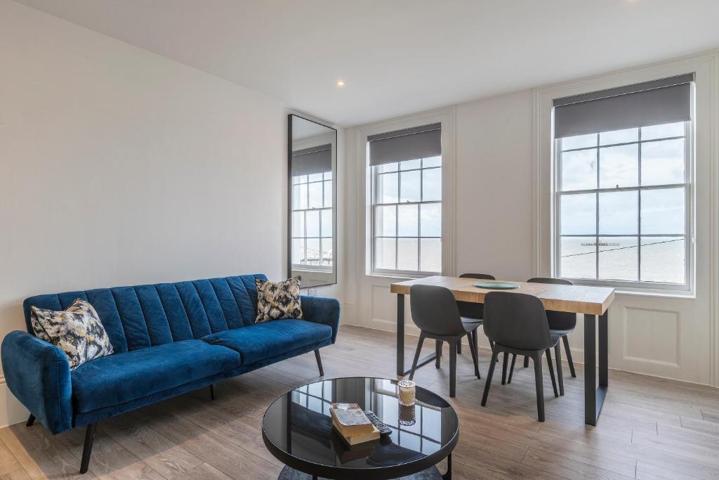 uma sala de estar com um sofá azul e uma mesa em Seaside Serenity: Stylish Sea View Apartments in Herne Bay em Kent
